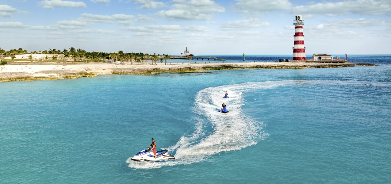 Jet skis near a lighthouse on a tropical island with clear blue waters | MSC Cruises