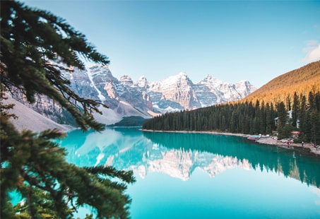 Turquoise lake surrounded by snow-capped mountains and evergreen trees | MSC Cruises Turquoise lake surrounded by snow-capped mountains and evergreen trees | MSC Cruises