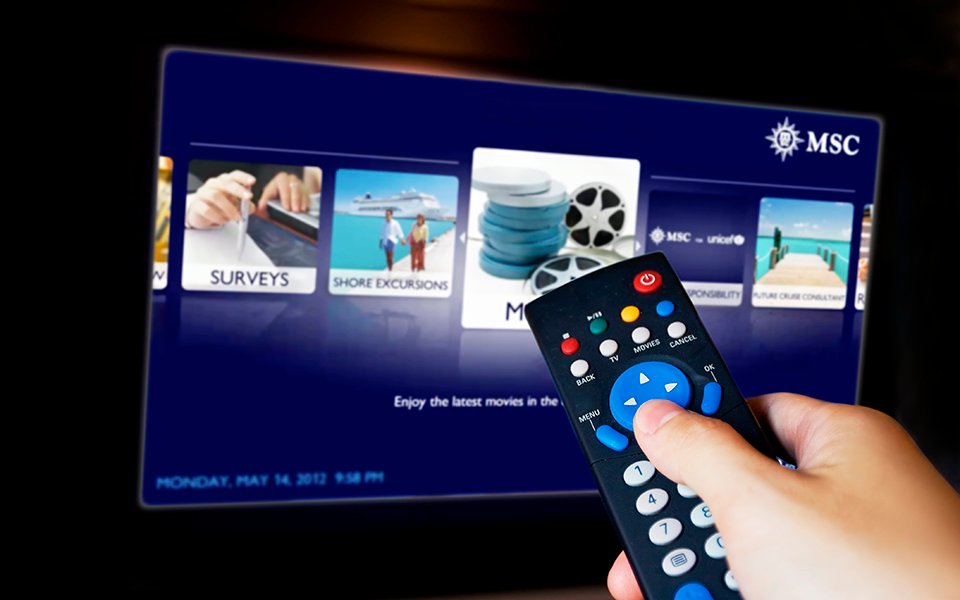 Hand using a remote to navigate MSC onboard entertainment options on a TV screen | MSC Cruises Hand using a remote to navigate MSC onboard entertainment options on a TV screen | MSC Cruises